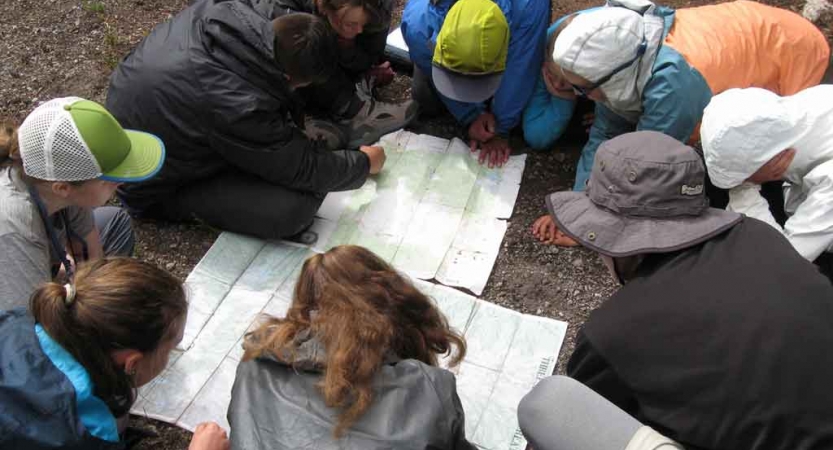 a group of outward bound students examine a map on a backpacking expedition in oregon
